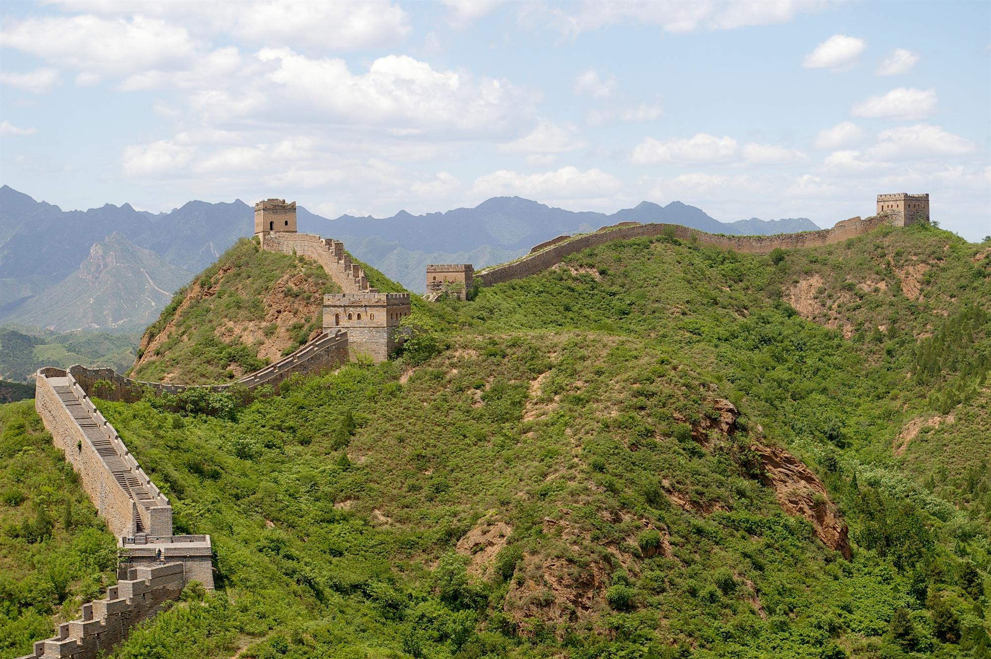 The Great Wall at Jinshanling winding over green hills, with watchtowers on the ridges
