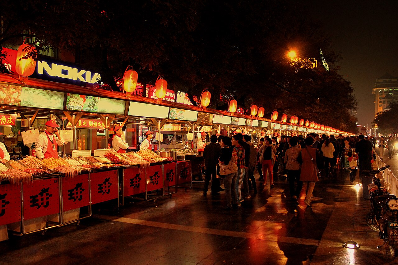 Food stalls under red lanterns at a night market in Beijing